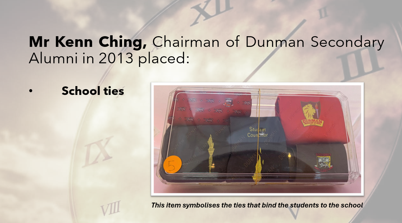 Dunman Secondary school ties in a clear box, including a navy Student Councillor tie with gold tassel and red ties.