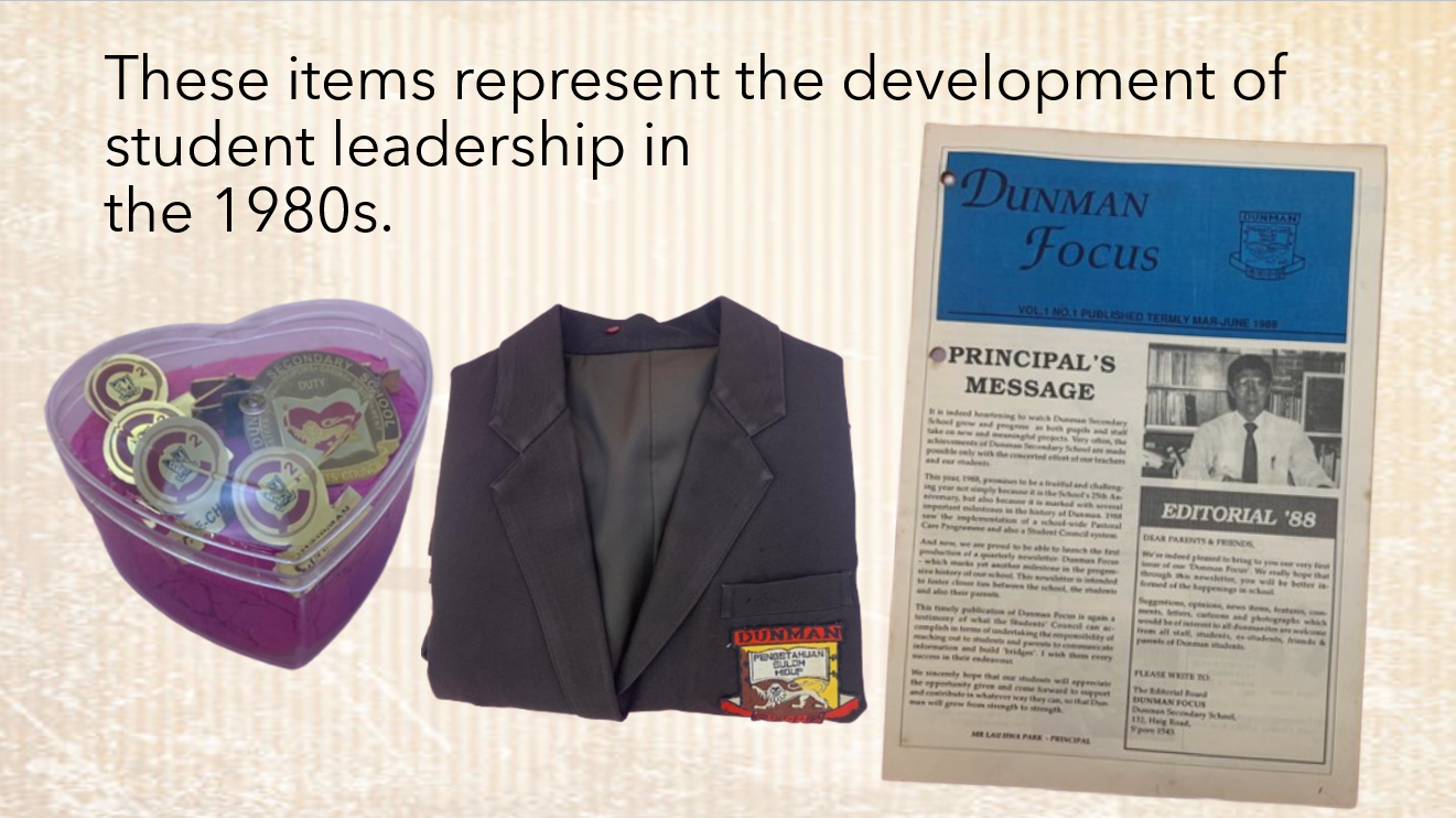 A heart-shaped box of badges, a dark school blazer, and the 1988 Dunman Focus newsletter representing 1980s student leadership.