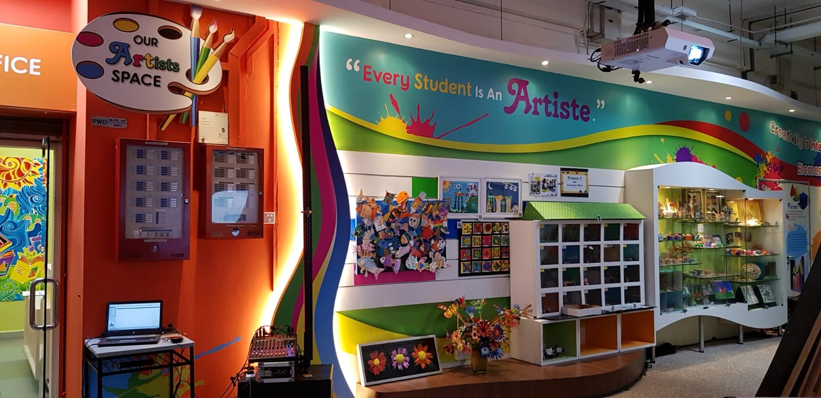 A colourful school arts display titled “Our Artists Space” showcases students’ artworks and creative pieces, alongside the message, “Every Student Is An Artiste.”
