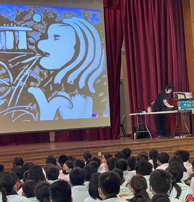 Students watch from the school hall as an artist creates a large image of the Merlion on screen during a live visual arts demonstration.
