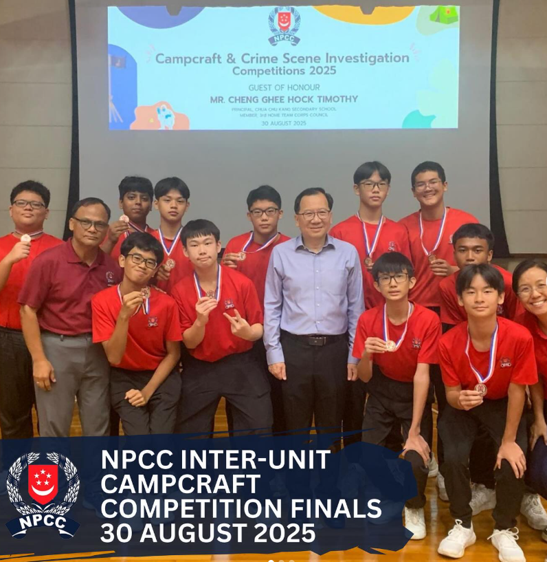 Group of students in red shirts wearing medals pose with adults at NPCC Campcraft Competition Finals 2025.