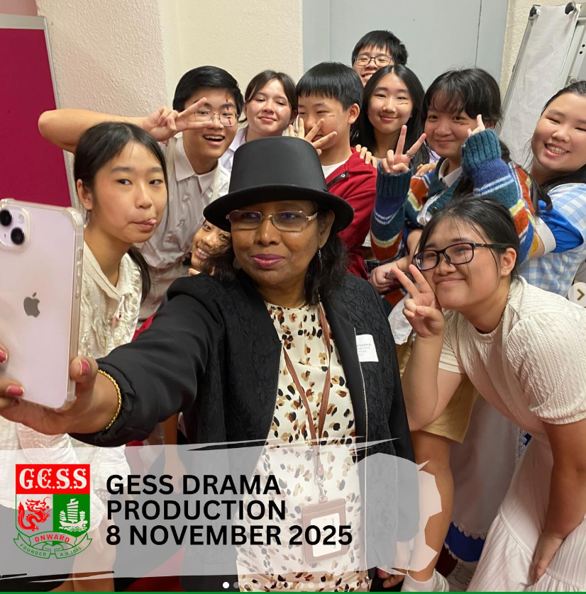 A woman in a black hat takes a selfie with a group of smiling students at GESS Drama Production, November 2025.