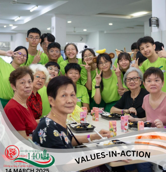 Group of students in green shirts and elderly women posing together at a table for a Values-in-Action event.