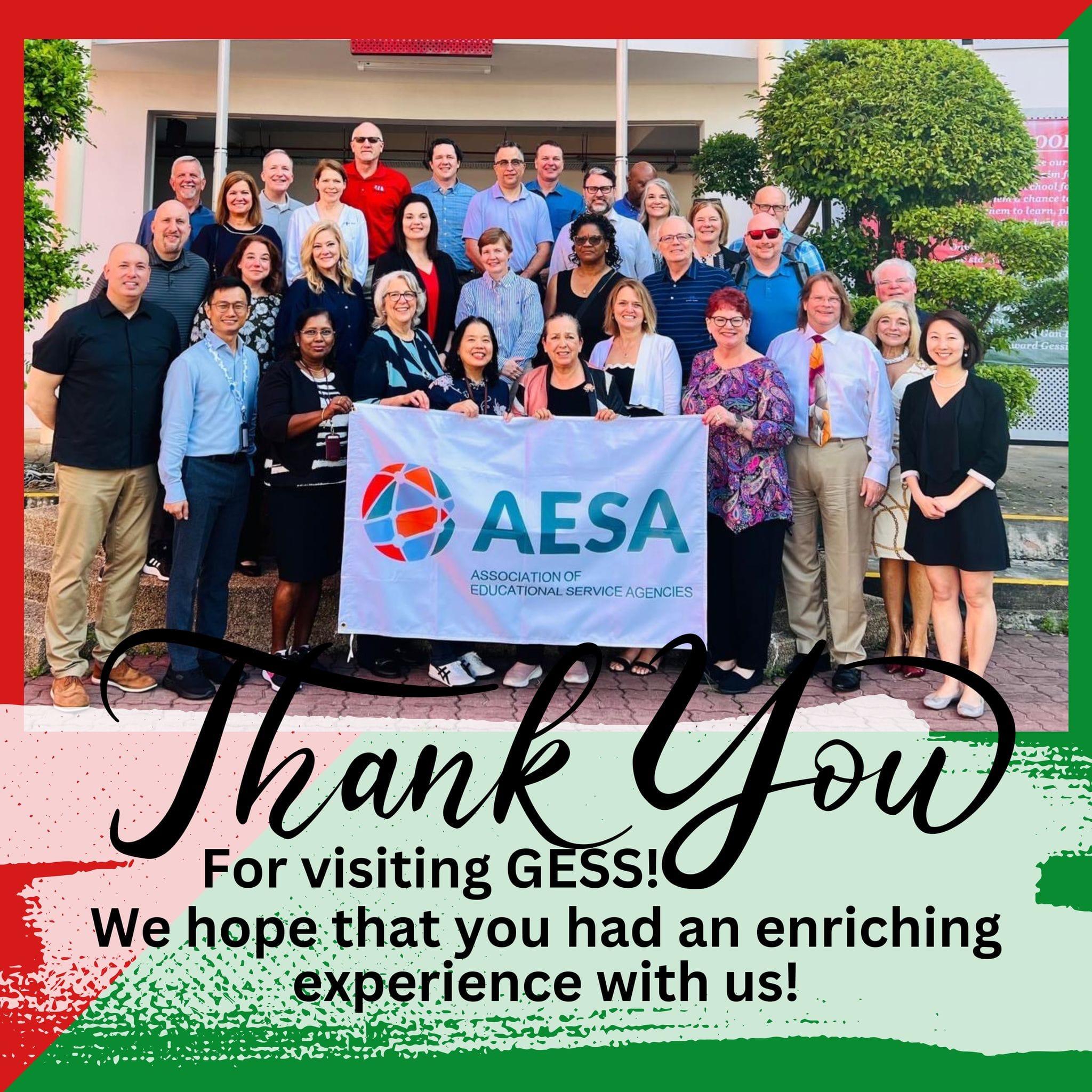 Large group of adults posing outdoors holding an AESA banner, with a Thank You for visiting GESS message below.