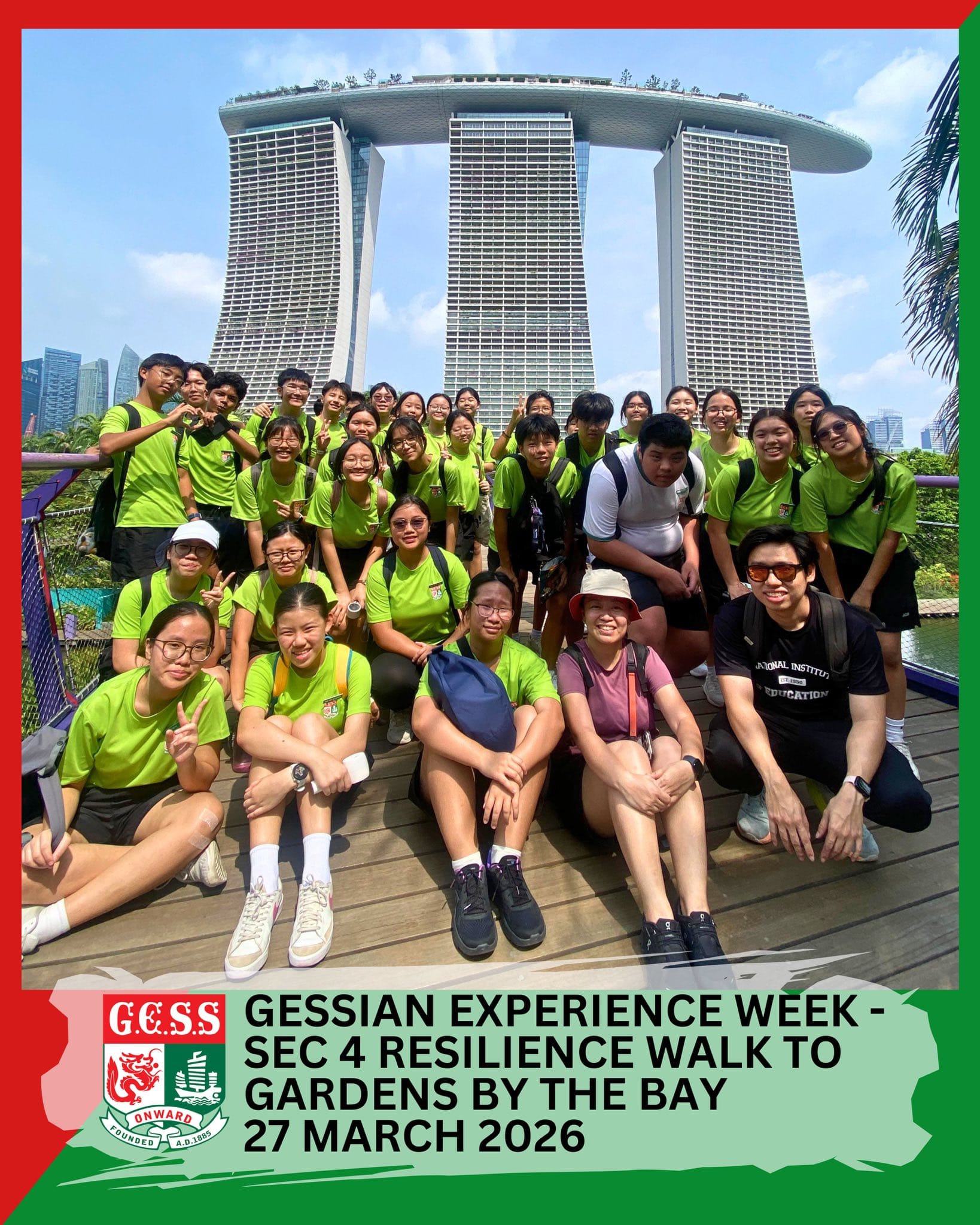 Large group of students in green shirts posing in front of Marina Bay Sands in Singapore.