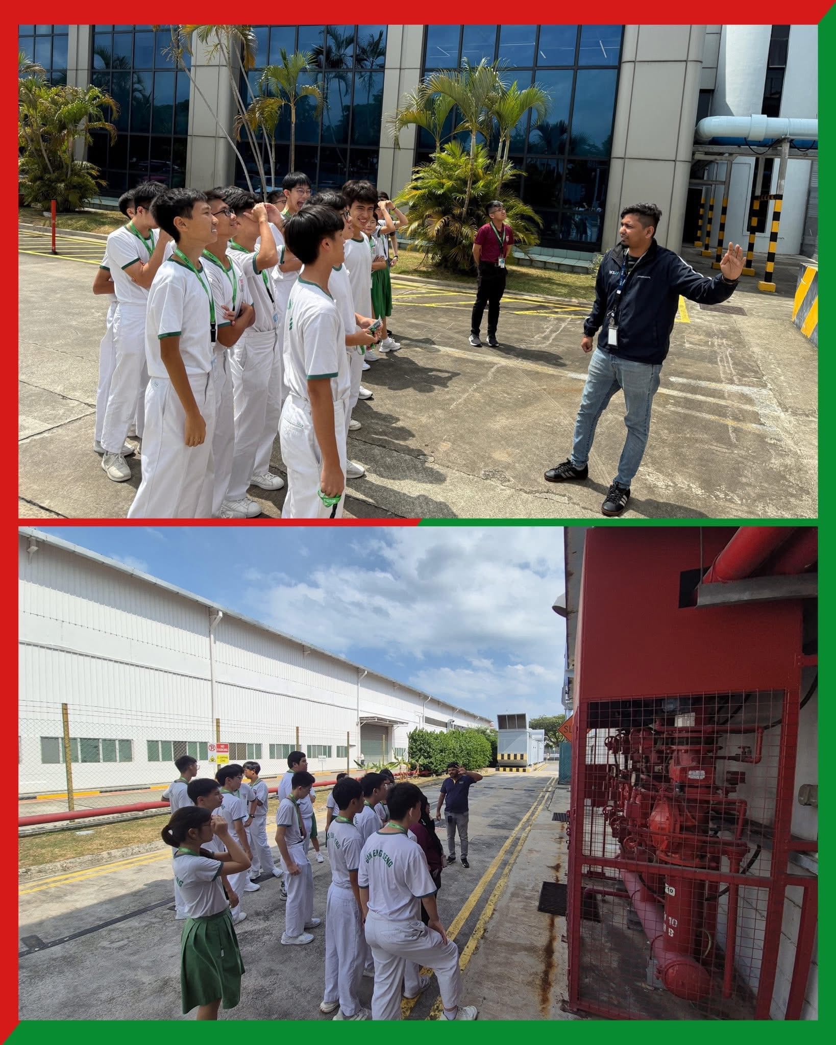 Students in white uniforms on an outdoor industrial facility tour, listening to a guide near red pipe equipment.
