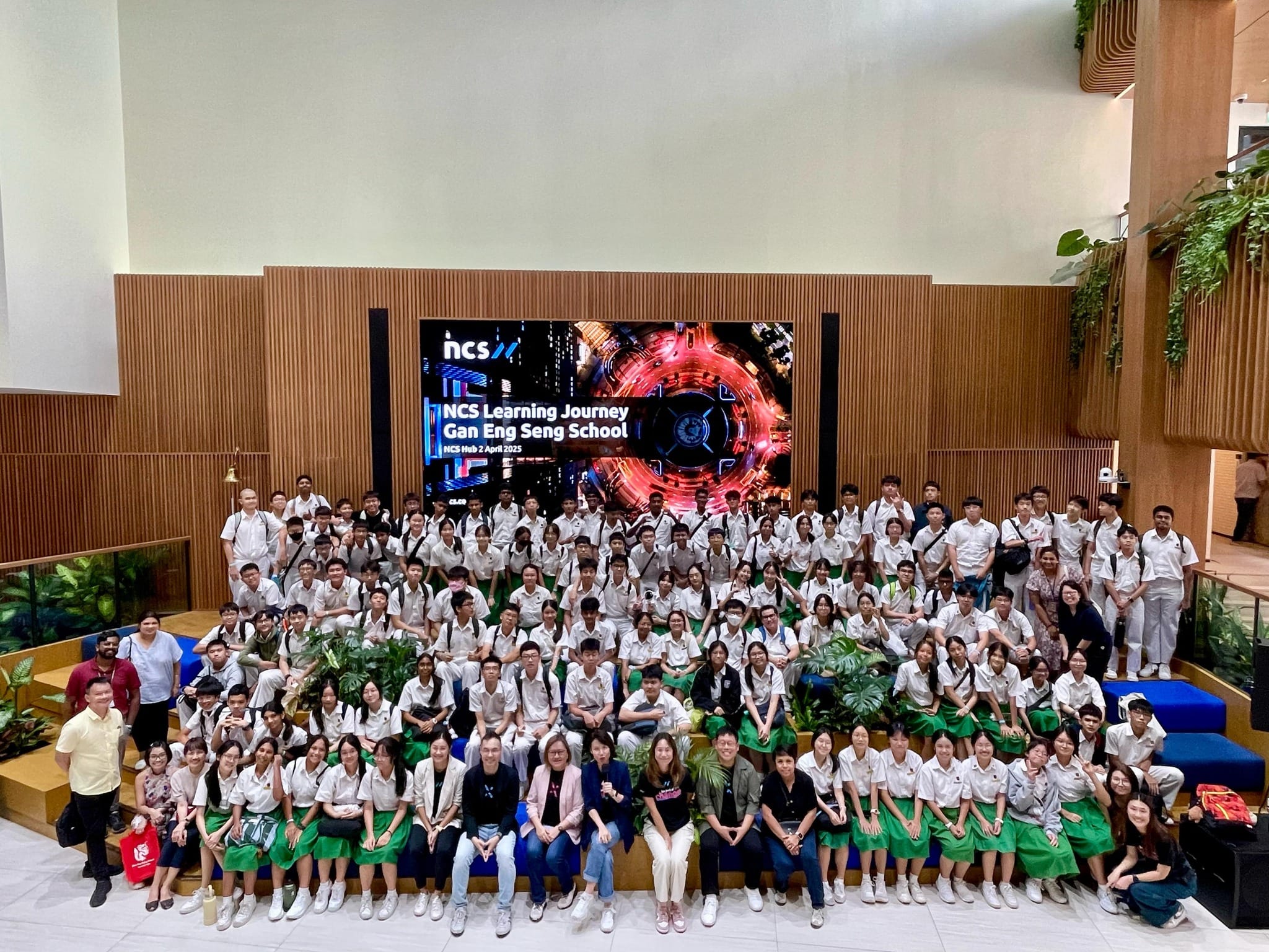 Large group of students in school uniforms posing indoors before an NCS screen reading NCS Learning Journey Gan Eng Seng School.