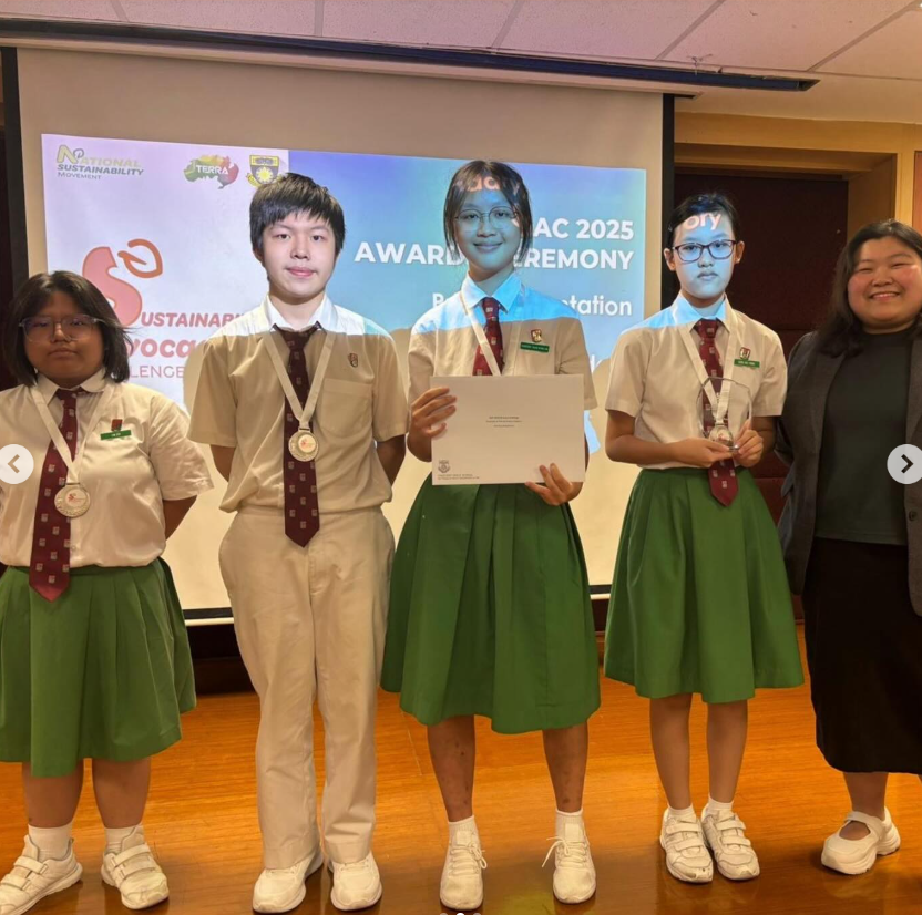 Four students in school uniforms with medals pose at an awards ceremony in 2025, one holding a certificate.
