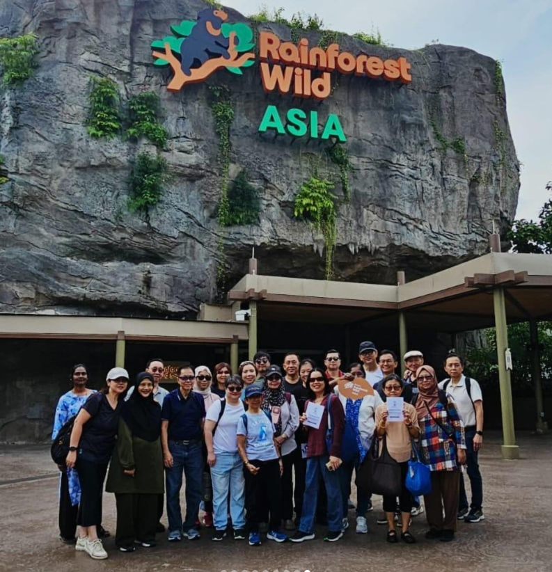 A large group of people posing in front of the Rainforest Wild Asia attraction entrance with a rocky facade.