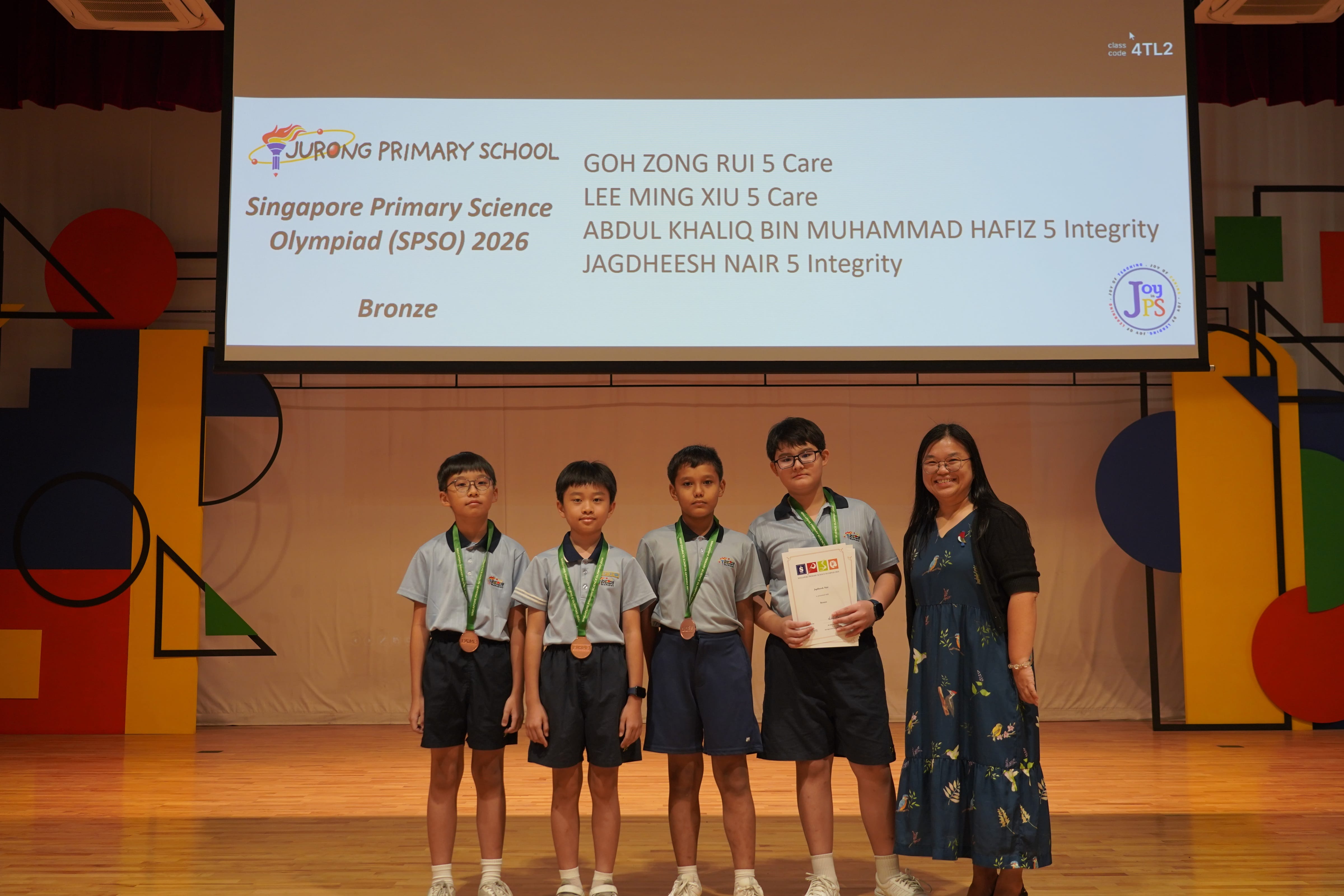 Four students with bronze medals and certificates with a Vice-Principal, SPSO 2026 winners.