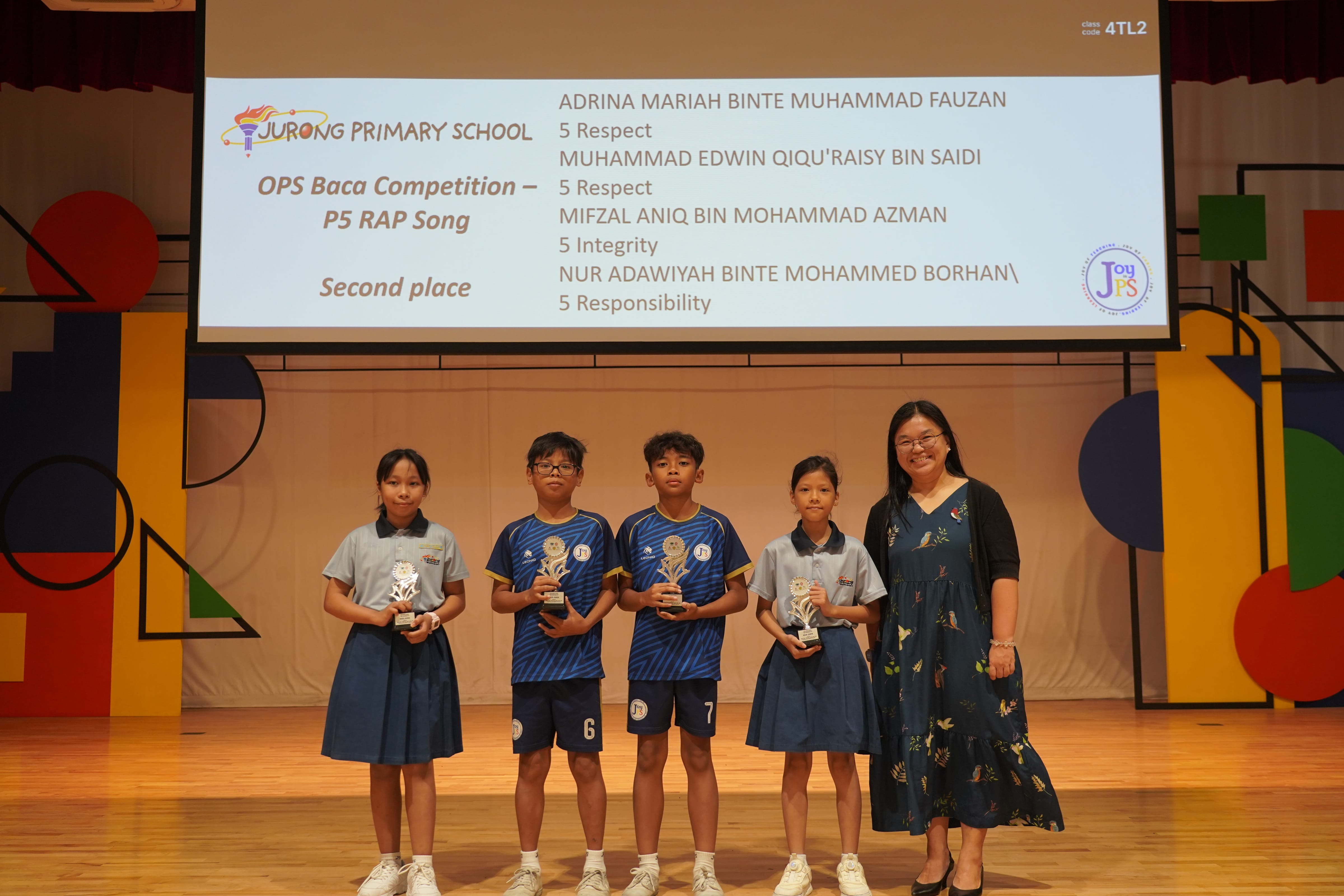 Four P5 students holding trophies with a Vice-Principal on stage, OPS Baca second place.