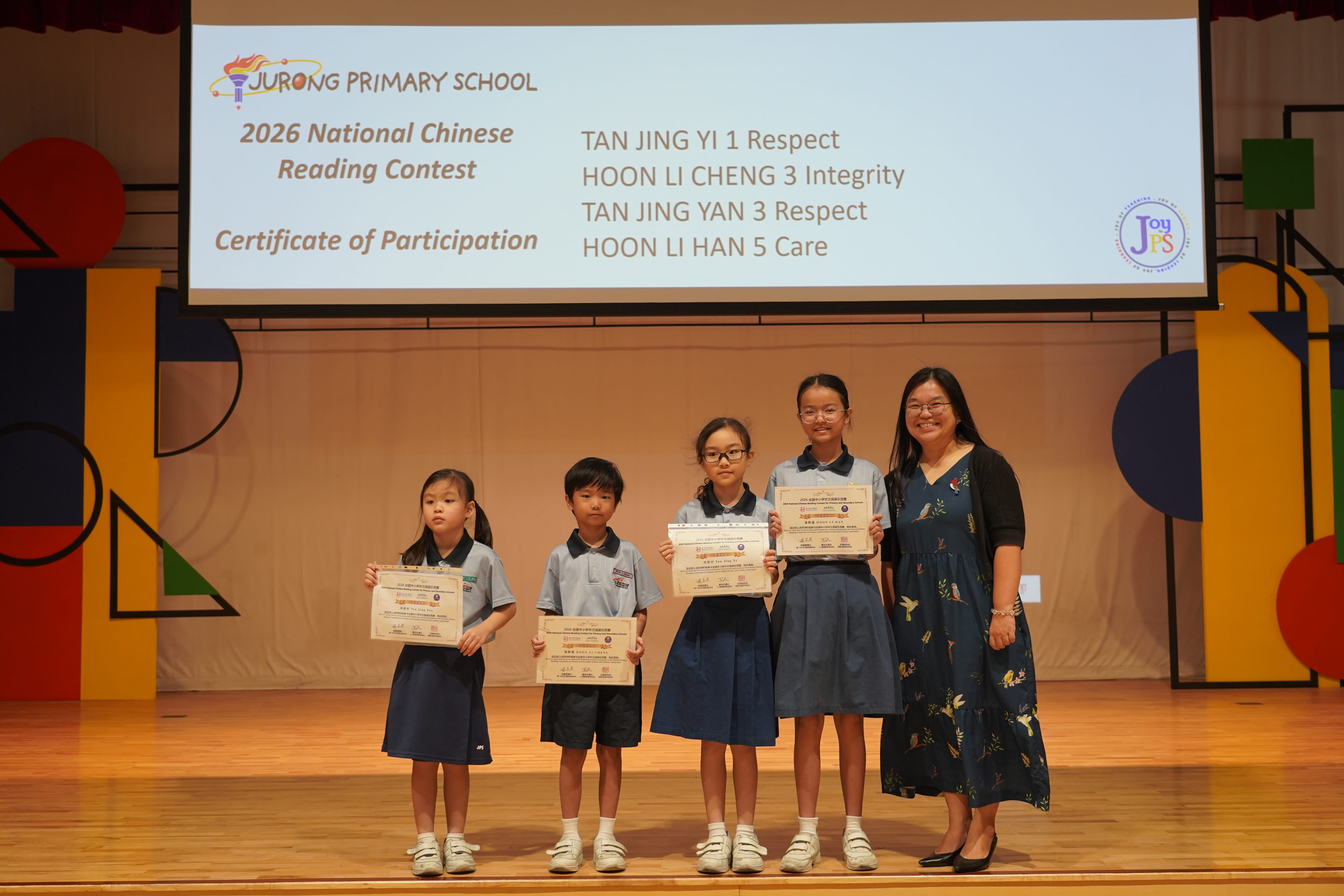 Four students holding certificates with a Vice-Principal on stage at Chinese Reading Contest.