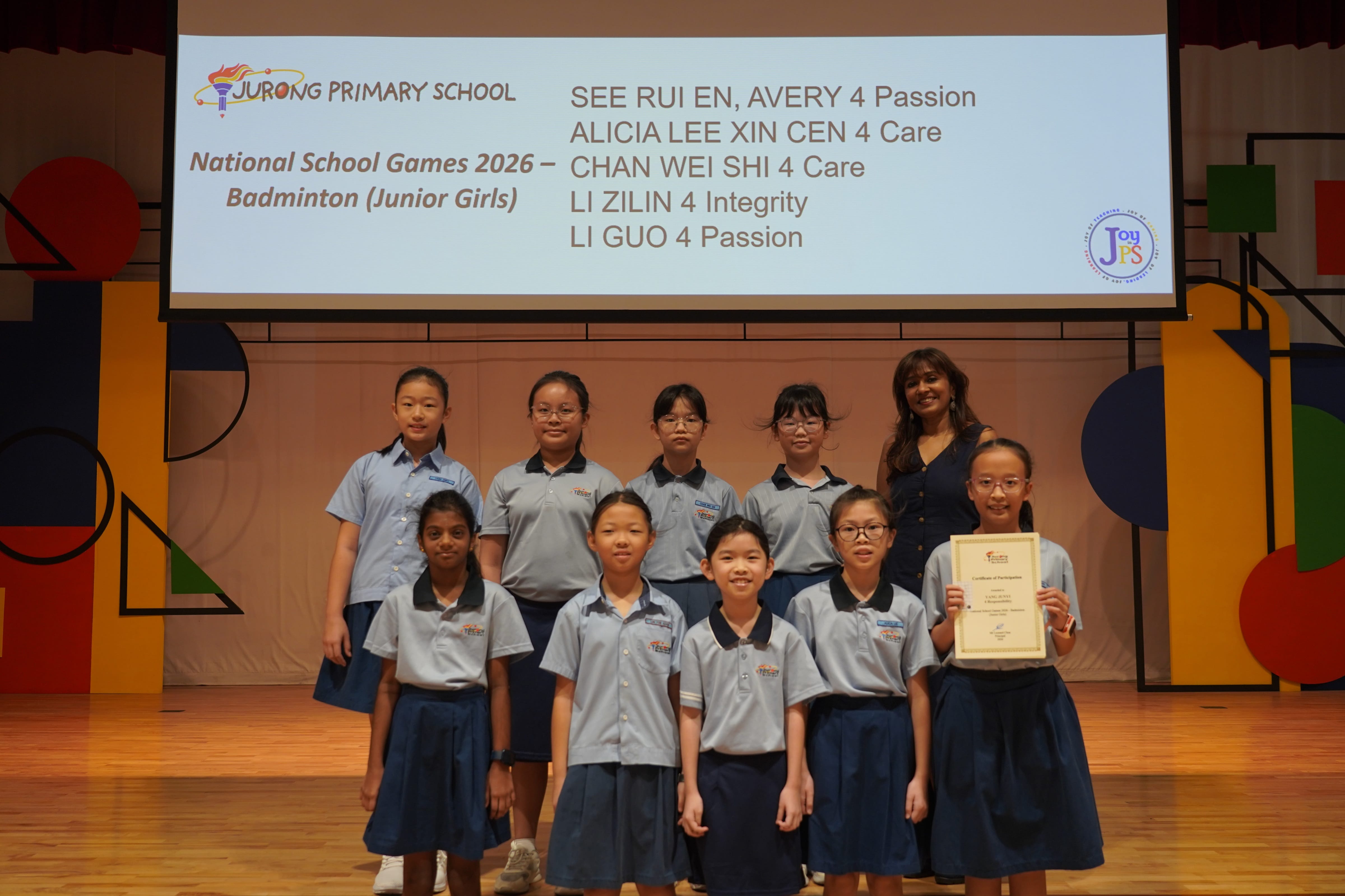 Nine girls with a certificate and Vice-Principal, National School Games 2026 Badminton Junior Girls award.