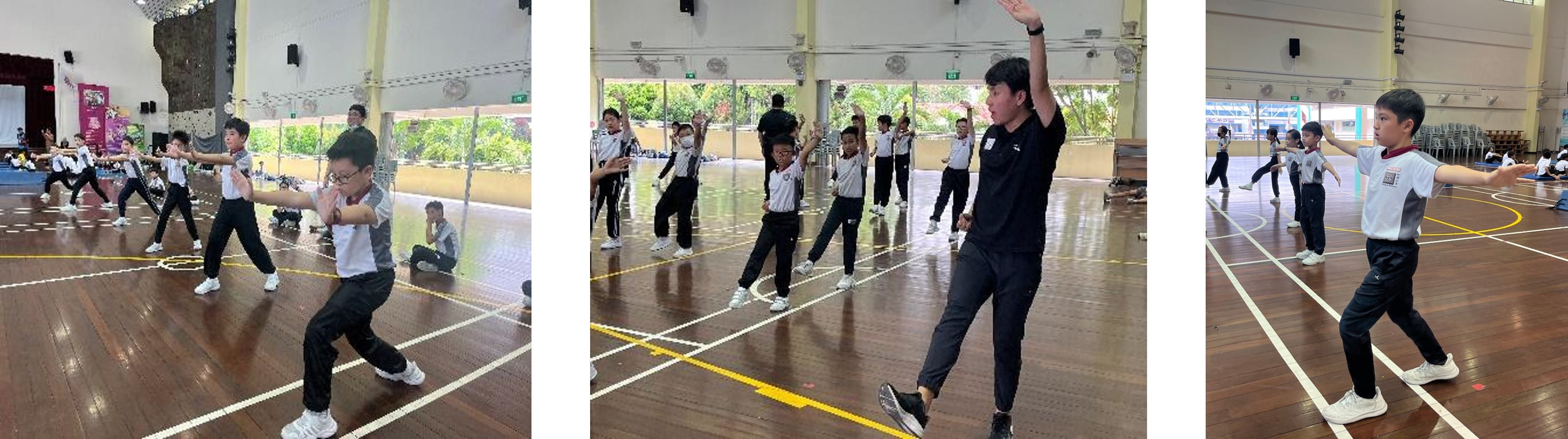 Children in school uniforms practice martial arts moves in an indoor gym, guided by an instructor in black.