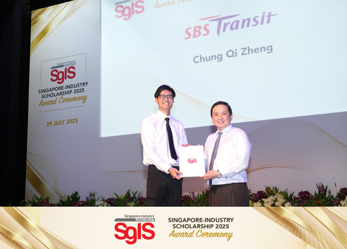 Two men in white shirts and ties hold a certificate together on stage at the SgIS Scholarship 2025 Award Ceremony.