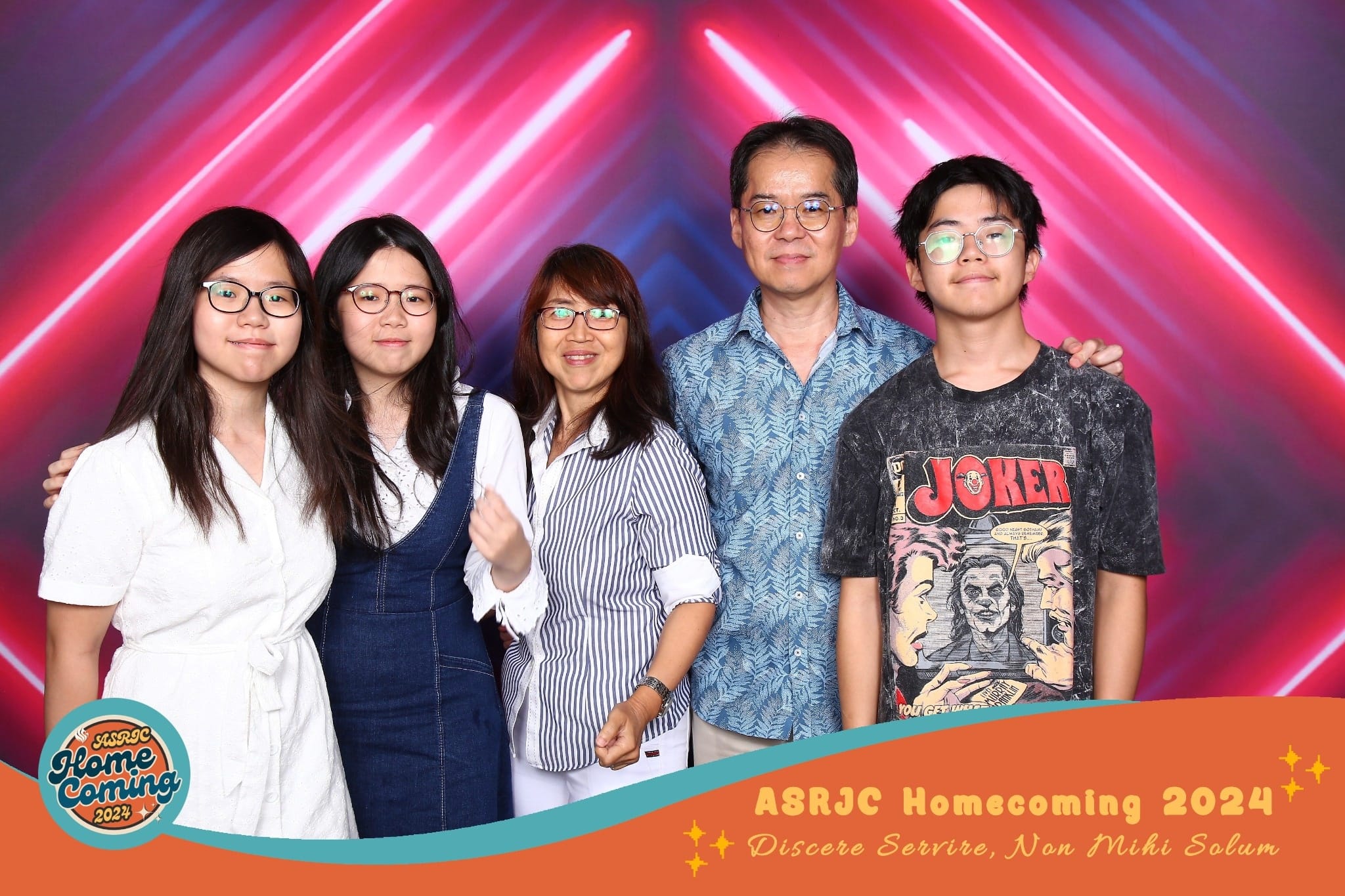 Five people pose together at ASRJC Homecoming 2024 in front of a pink and blue neon light backdrop.