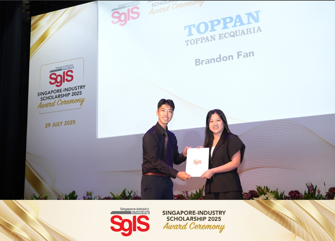 Two people in black attire hold a white SgIS bag on stage at the Singapore-Industry Scholarship 2025 Award Ceremony.