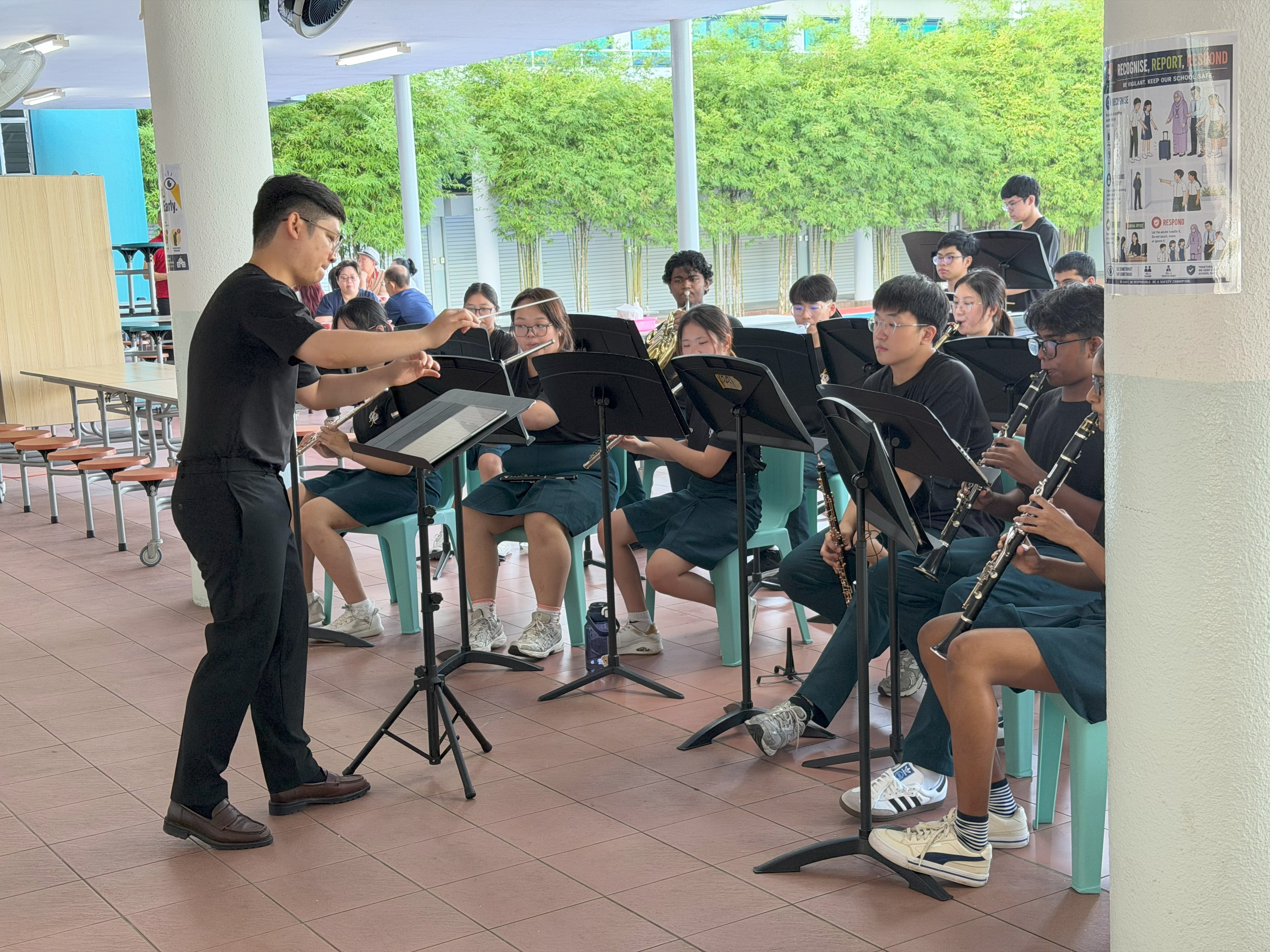 A young man conducts a student band indoors