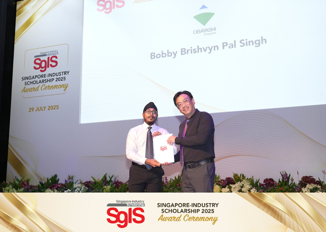 Two men shake hands holding an award folder on stage at the Singapore-Industry Scholarship 2025 ceremony on 29 July 2025.