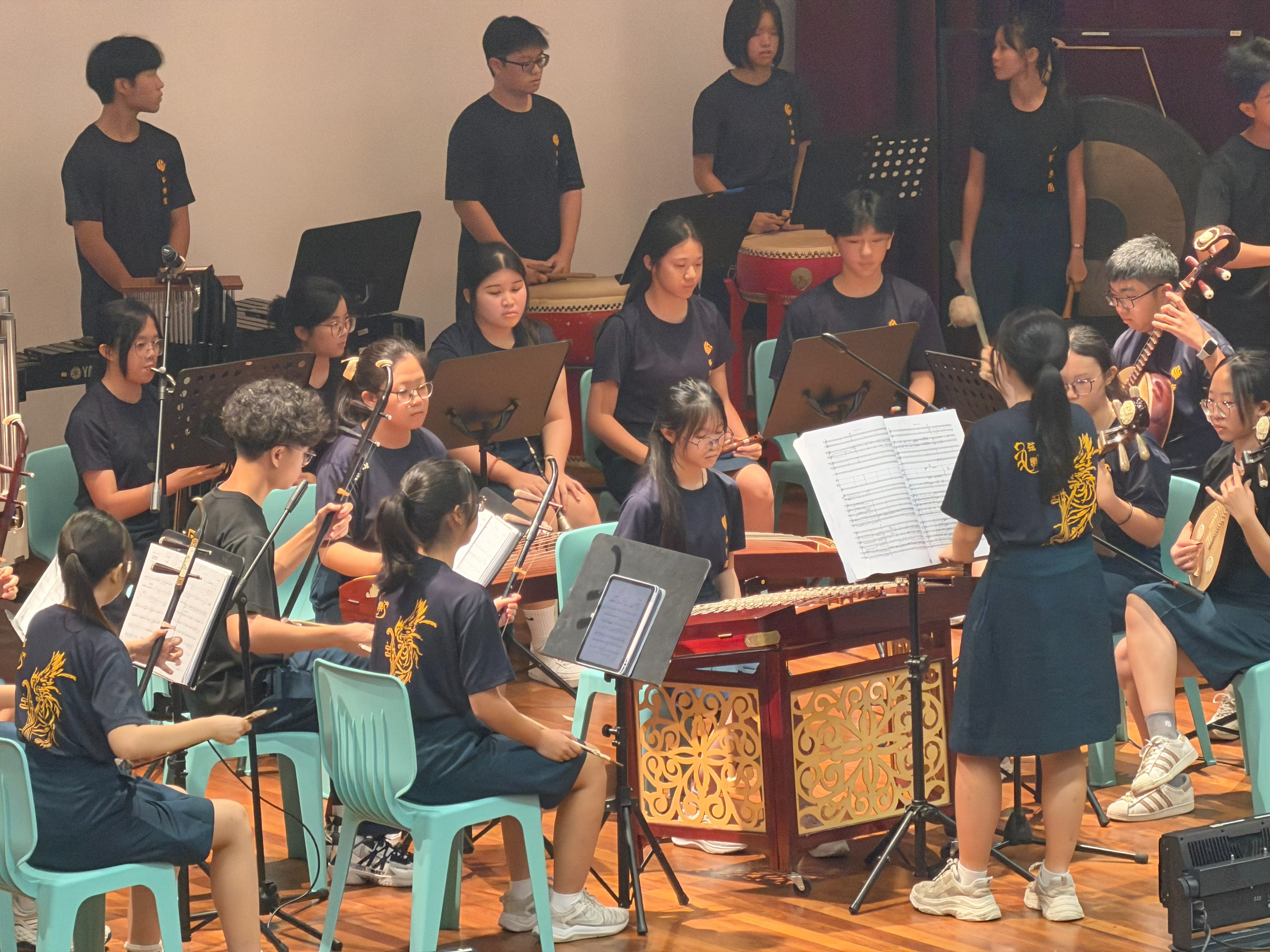 A female student conducts the college Chinese Orchestra in a performance on stage