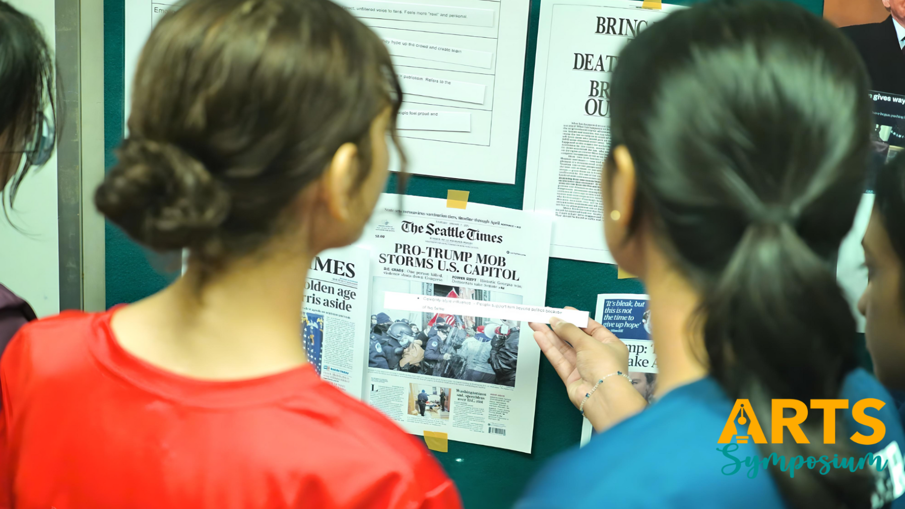 Two people view a bulletin board displaying a Seattle Times front page headlined "Pro-Trump Mob Storms U.S. Capitol."