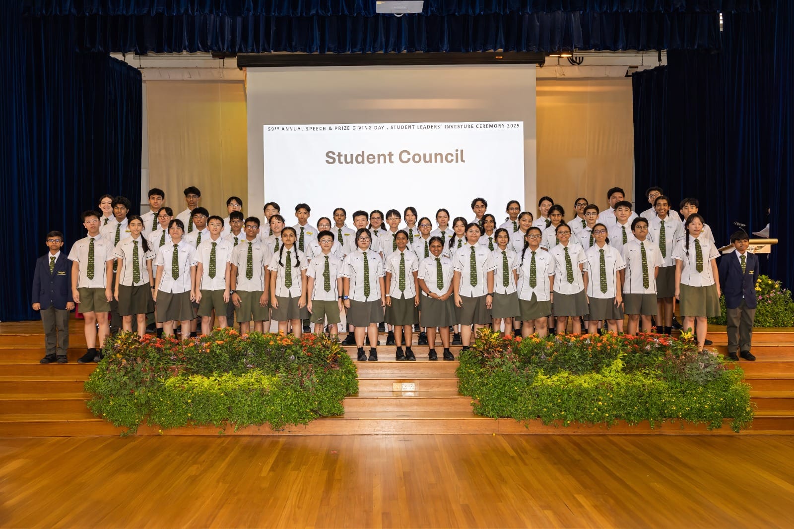 Large group of uniformed students posed on a stage in front of a screen reading Student Council at a 2025 ceremony.