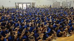 NV students wearing matching blue shirts sitting on the floor of the school hall.