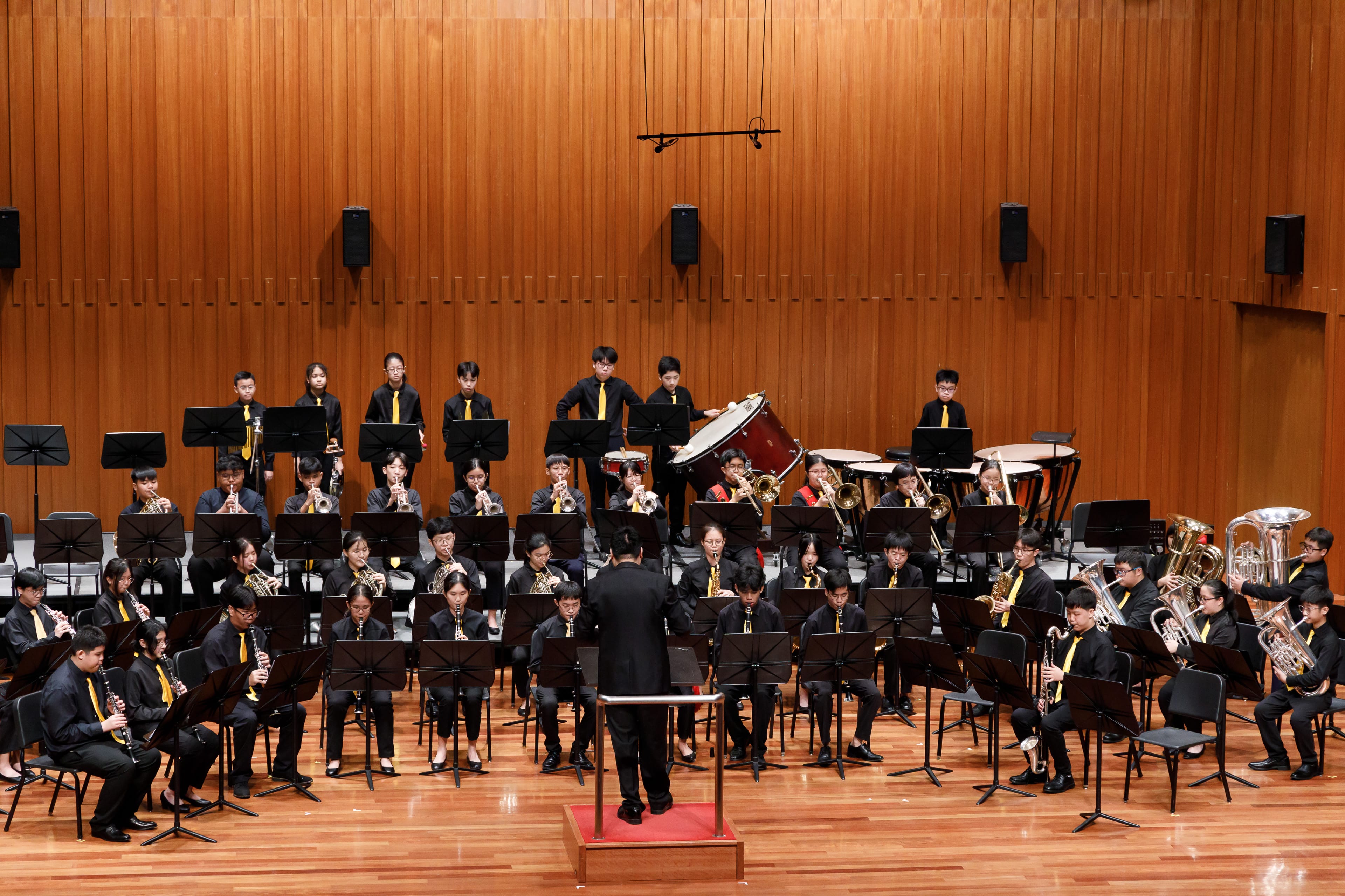 Band members perform led by a conductor on a podium during the SYF Competition.