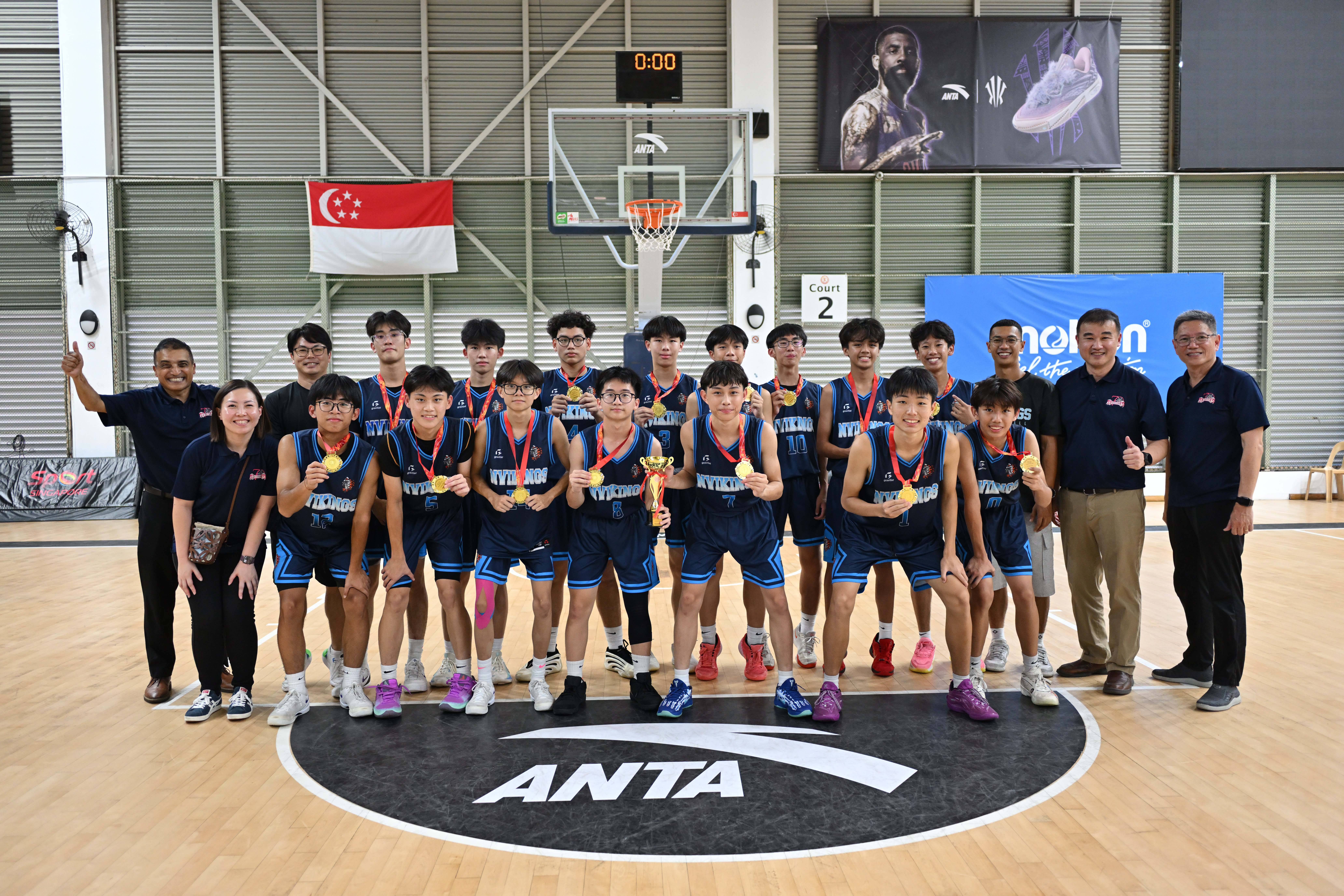 The NV B Division Boys Basketball team posing for photo with the school leaders on the court after winning the North Zone title with a 70–64 victory.
