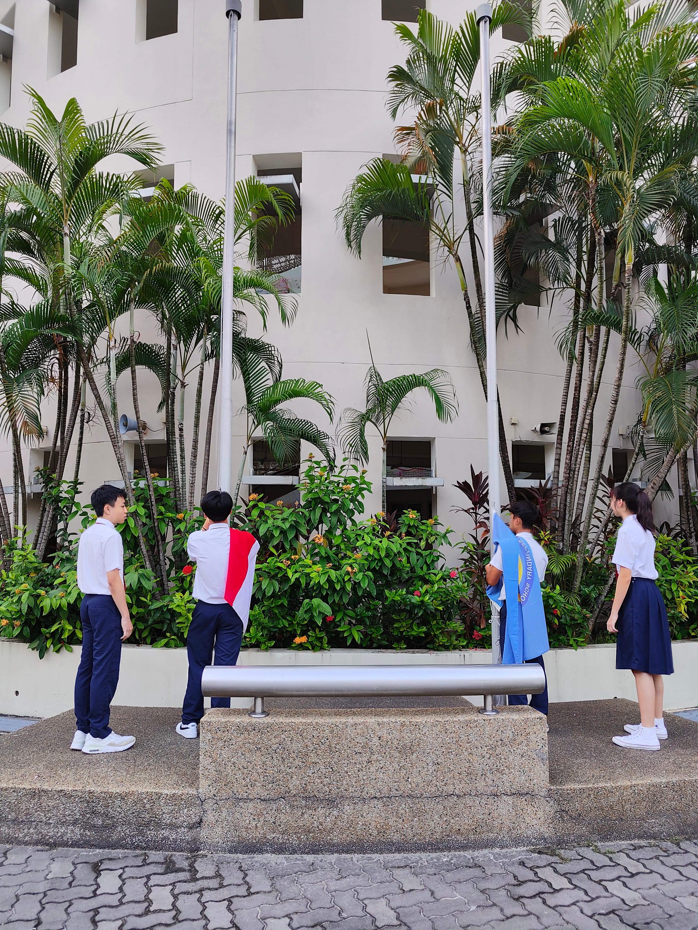 NV students stand by flagpoles in the school's parade square