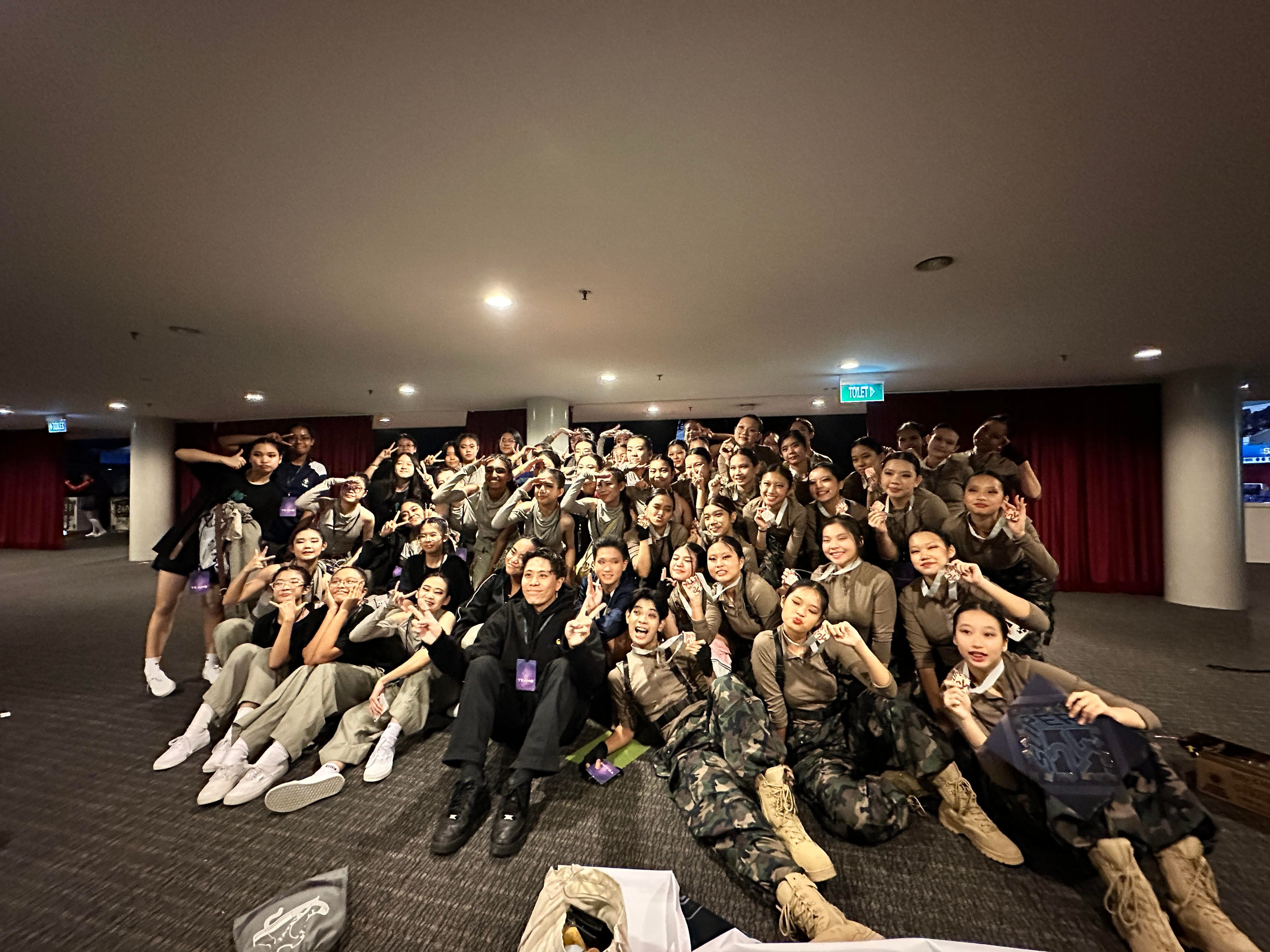 NV Boogie Crew in matching tan and camouflage outfits posing together indoors near a red curtain.