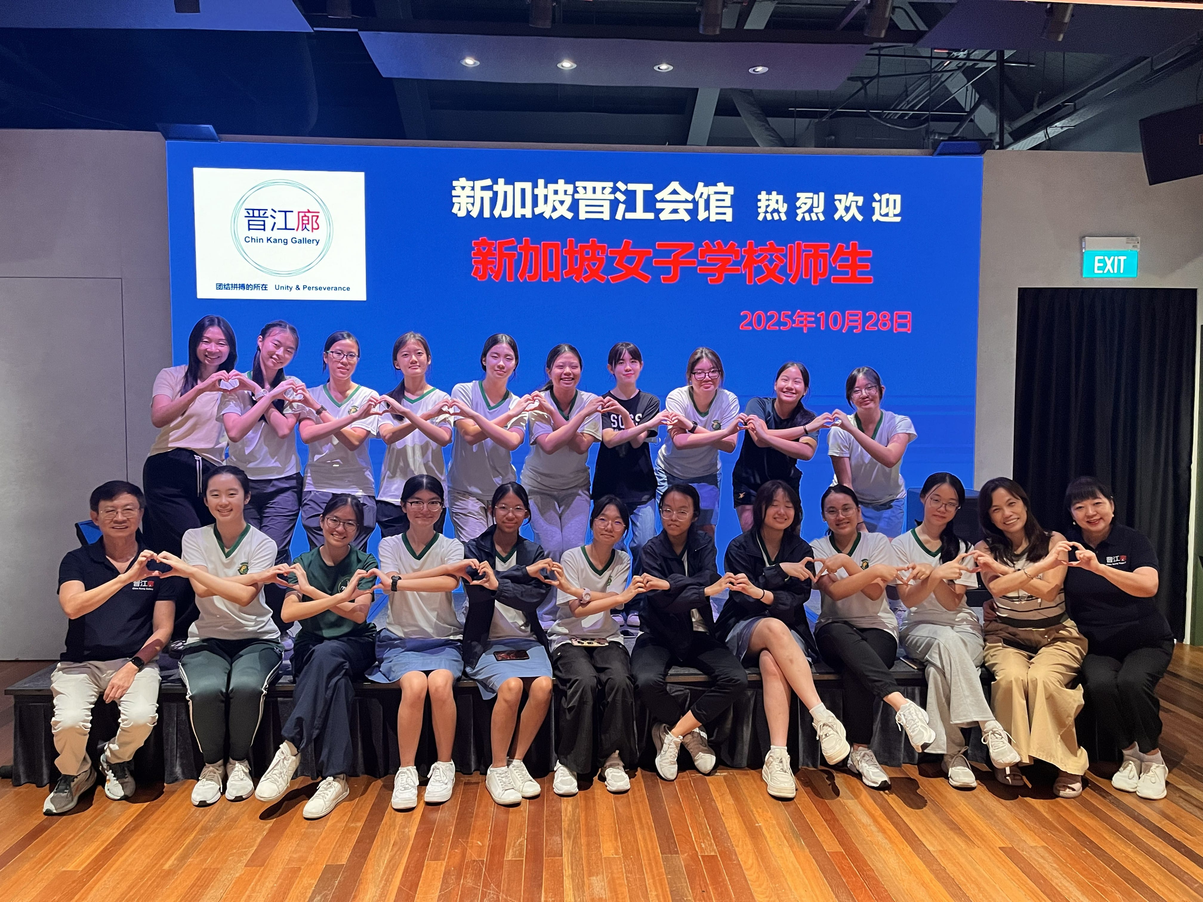 Seven people pose together holding colorful Chinese-language project boards in front of school display panels.