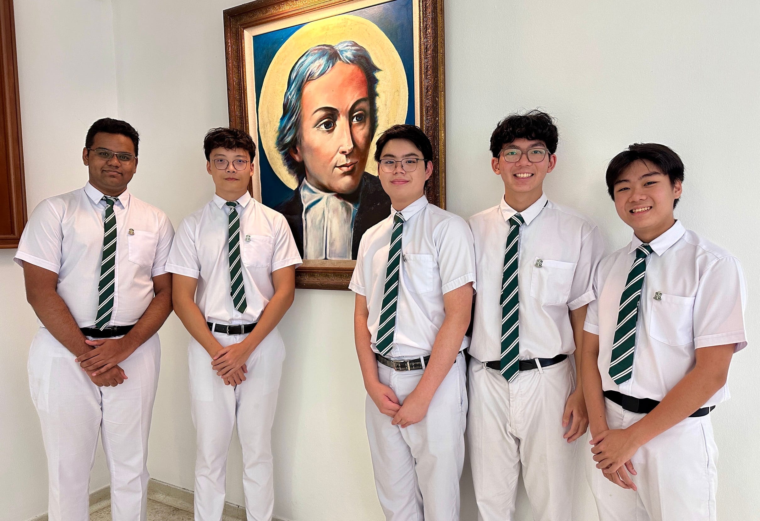 Five male students in white uniforms with green striped ties stand before a framed painted portrait of a saint.