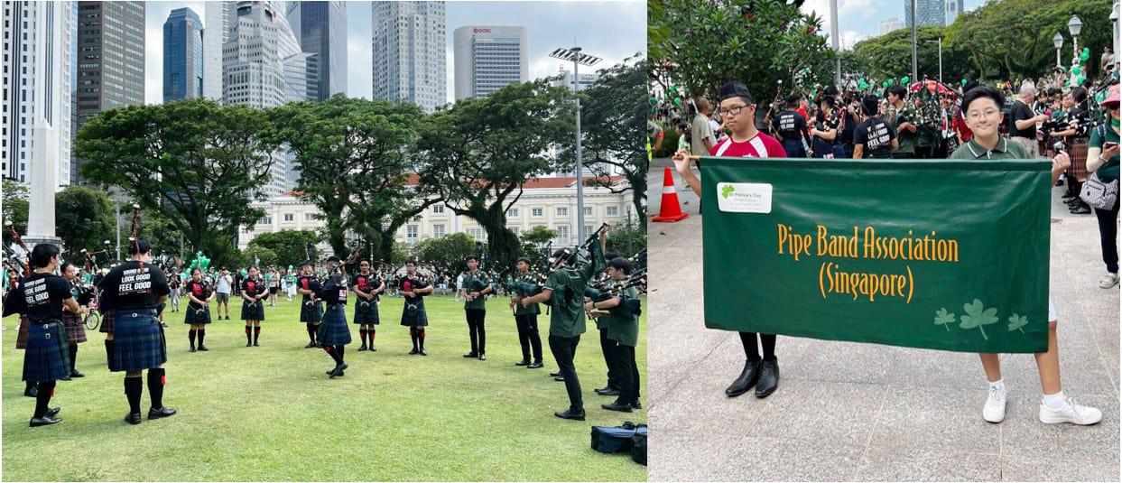 Two students hold a green Pipe Band Association Singapore banner at a parade, while bagpipers in kilts perform outdoors.