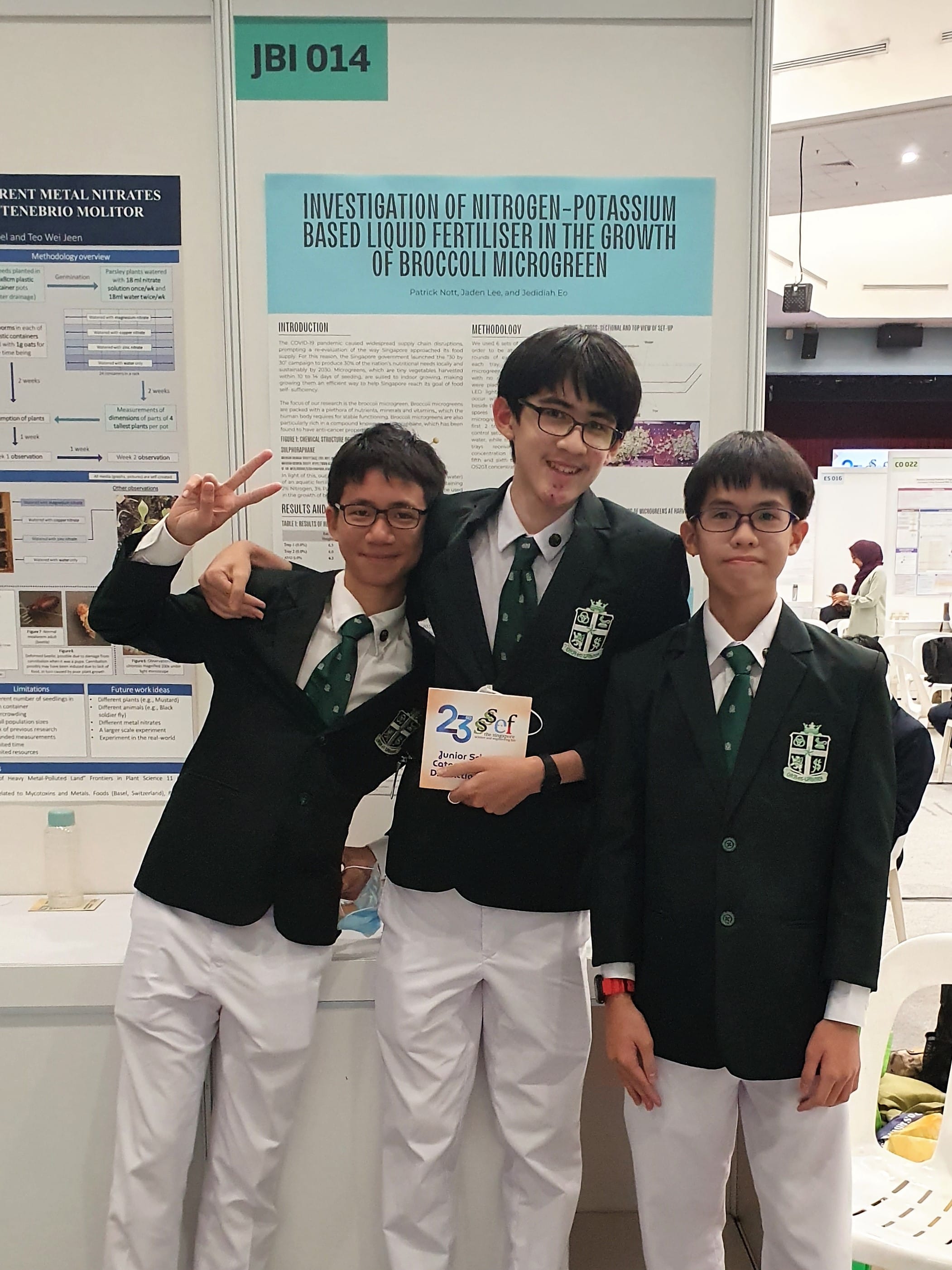 Three students pose beside their SSEF poster on nitrogen-potassium fertiliser effects on broccoli microgreens, board JBI 014.