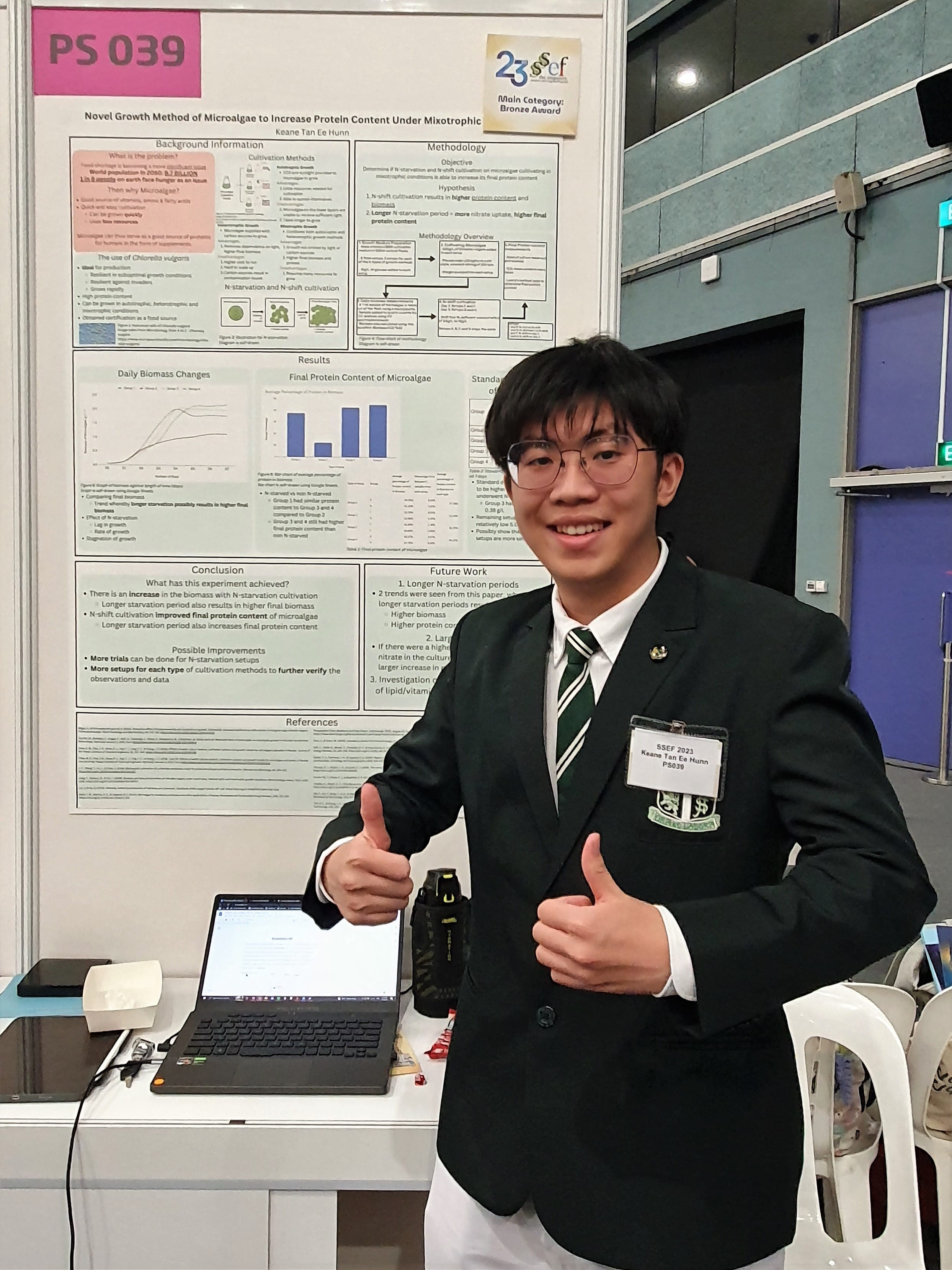 Keane Tan gives a thumbs up beside his SSEF poster on growing microalgae to boost protein content, with a Bronze Award, board PS 039.