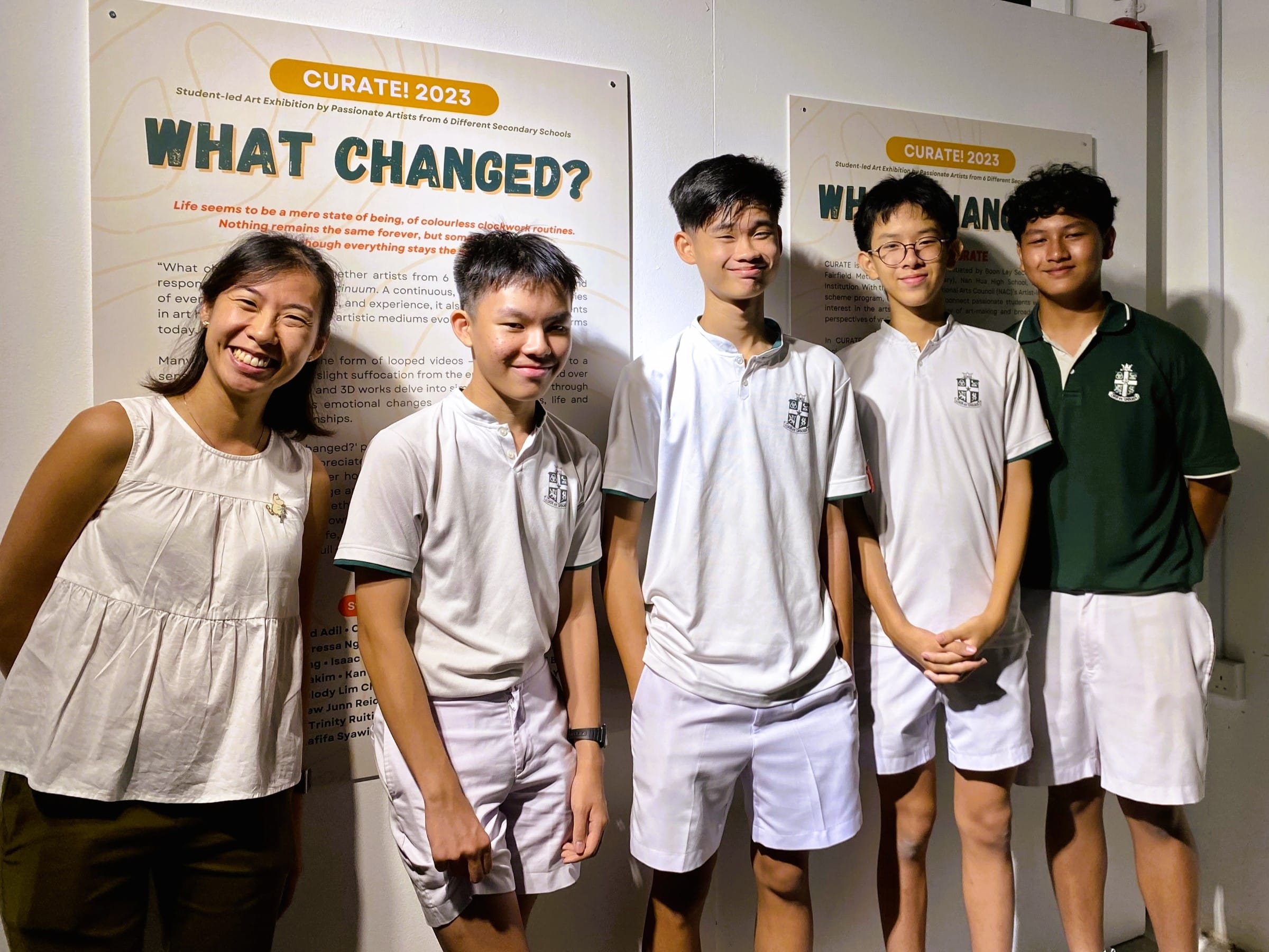 Five smiling students stand before a "Curate! 2023 What Changed?" student art exhibition poster.