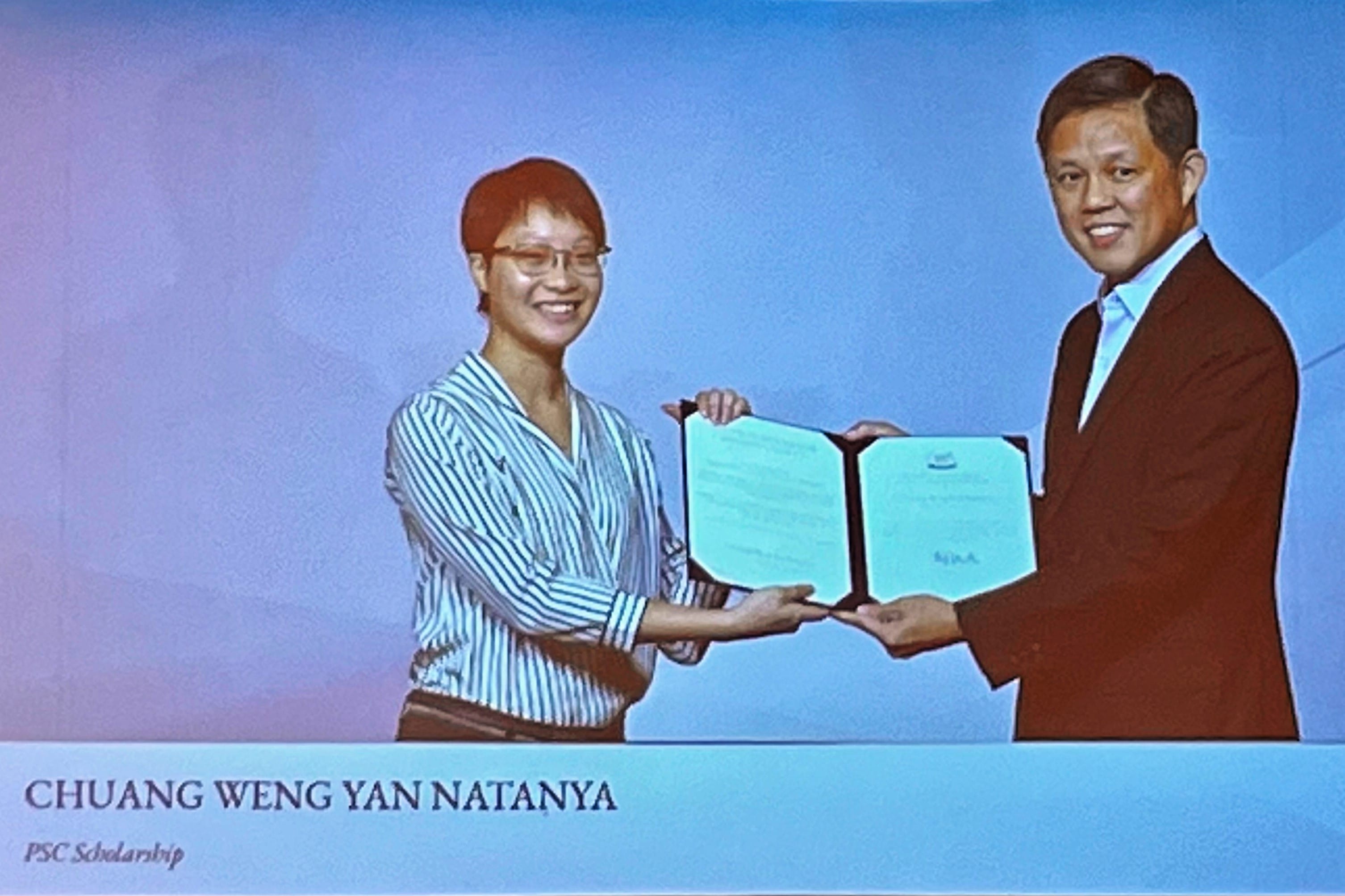 Chuang Weng Yan Natanya receiving a PSC Scholarship certificate from a man, both smiling.