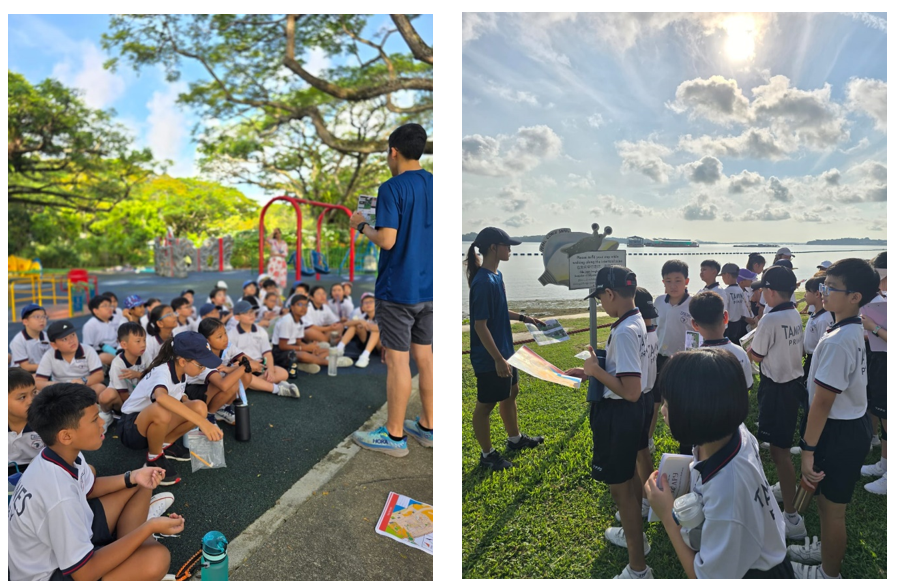 Students in white uniforms sit on pavement near a playground while an instructor stands, and gather by a waterfront sign.