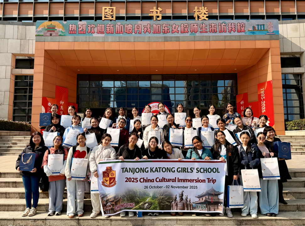 A large group of girls pose on steps holding a banner for Tanjong Katong Girls' School 2025 China Cultural Immersion Trip.