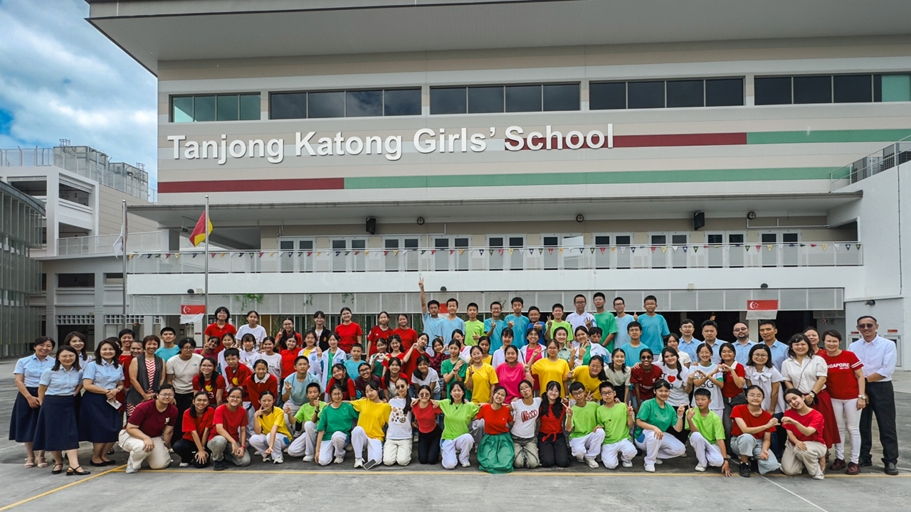Large group of students and teachers posing outside Tanjong Katong Girls' School building.