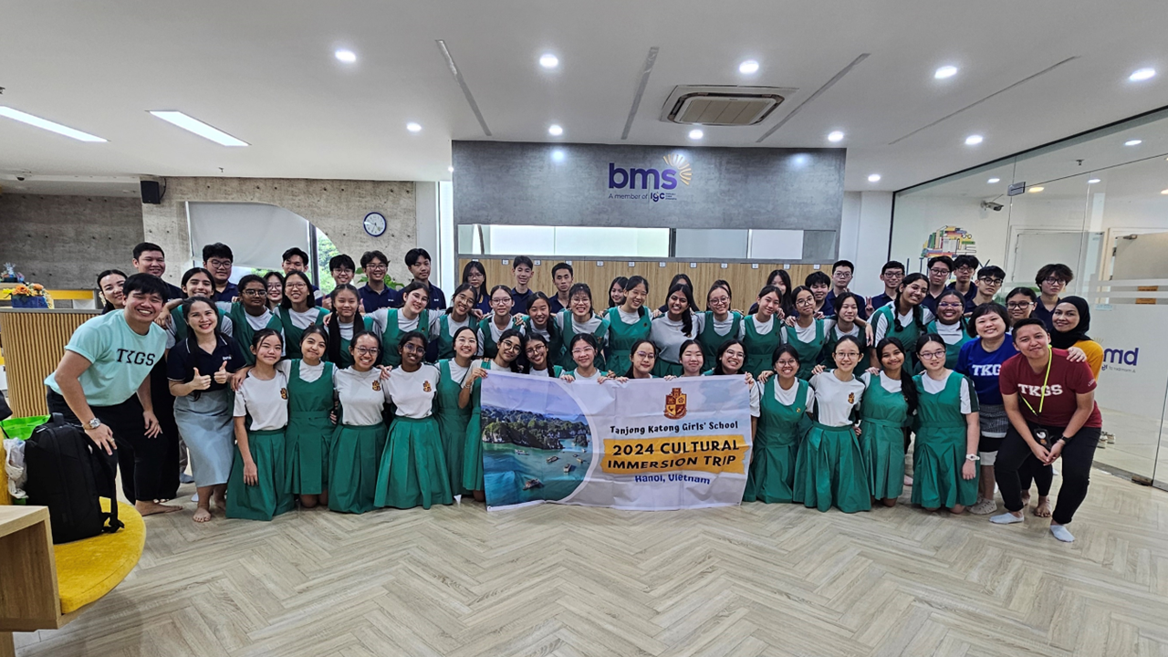 Large group of students in green uniforms holding a Tanjong Katong Girls' School 2024 Cultural Immersion Trip banner.