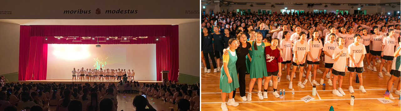 Students perform on a red-curtained stage while a large crowd of TKGS-shirted students fills a school hall.