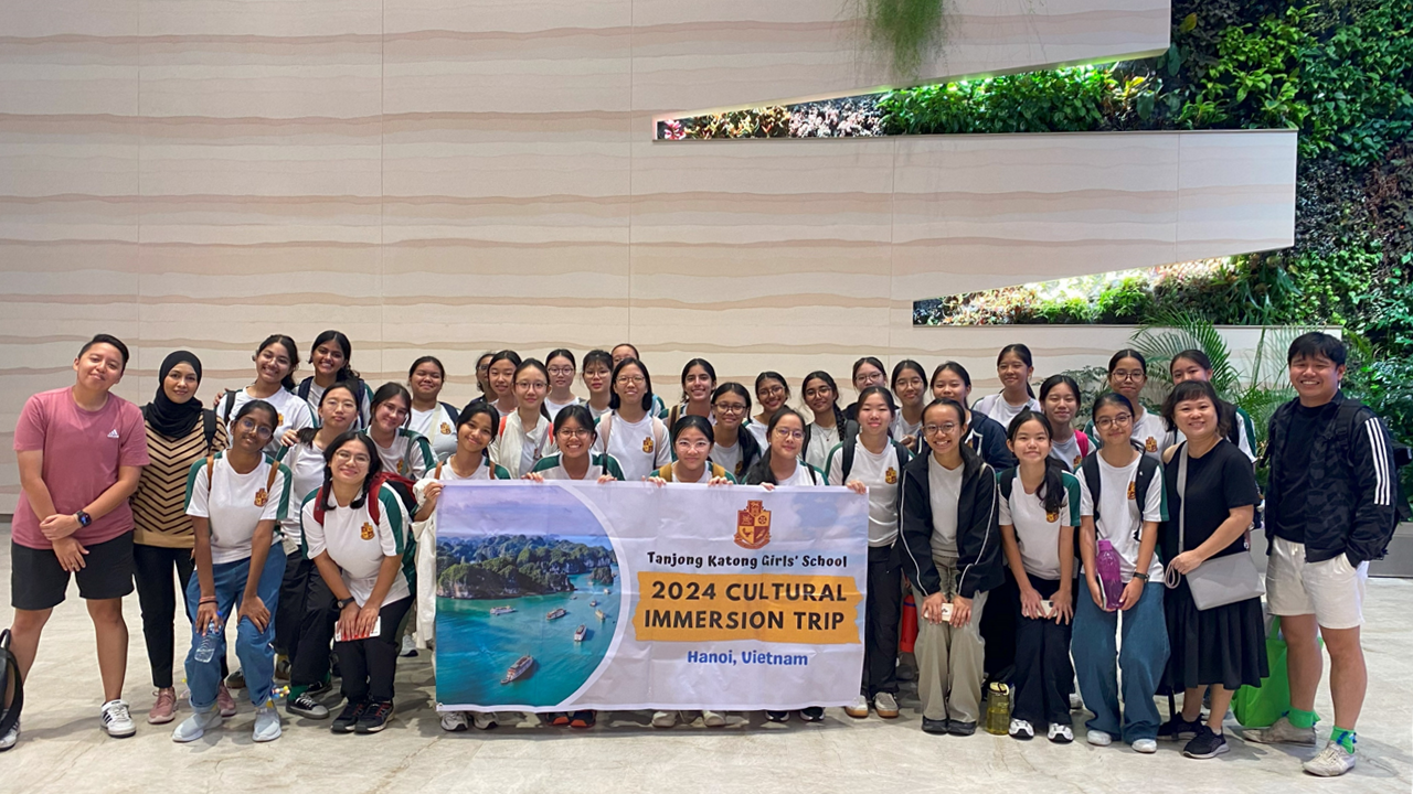 Large group of students holding a banner reading Tanjong Katong Girls' School 2024 Cultural Immersion Trip Hanoi Vietnam.