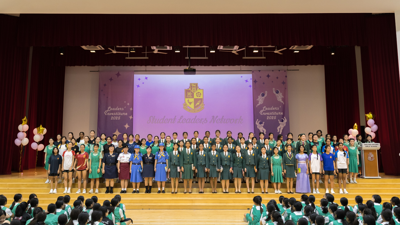 Large group of school girls in various uniforms on a stage at a Student Leaders Network Leaders Investiture 2025 ceremony.