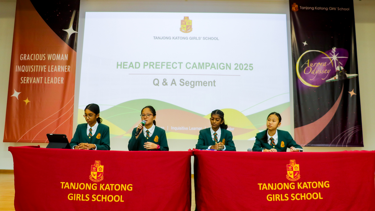 Four uniformed girls sit at a red-draped table during Tanjong Katong Girls School Head Prefect Campaign 2025 Q&A.