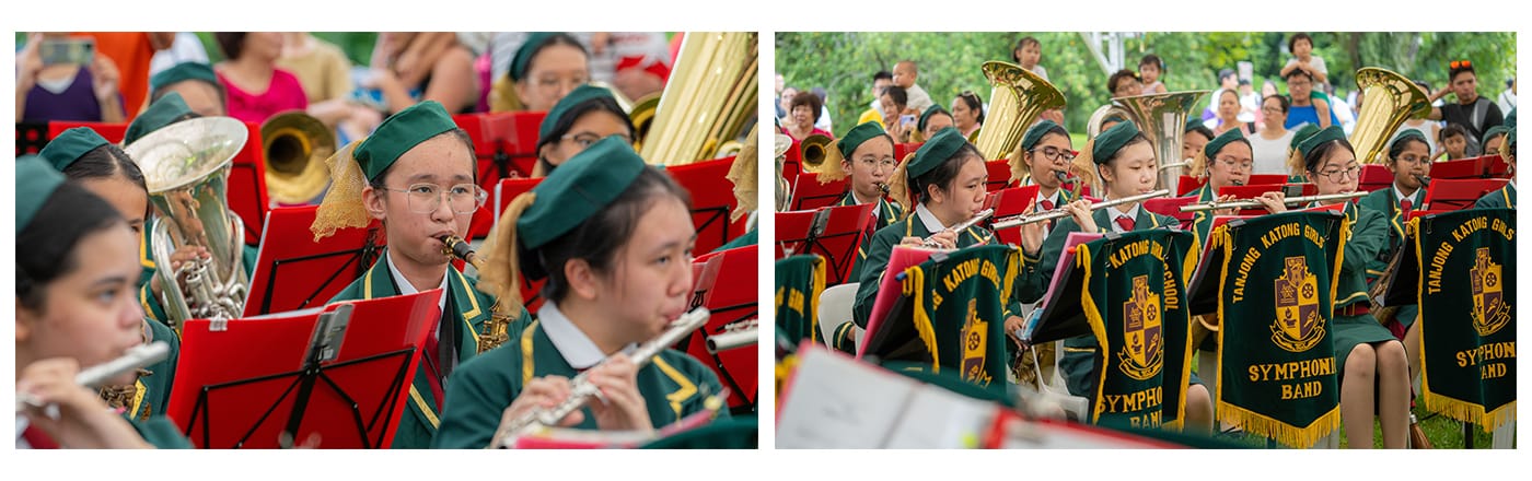 Students in green uniforms and hats perform as the Tanjong Katong Girls Symphonic Band outdoors with brass and flute instruments.