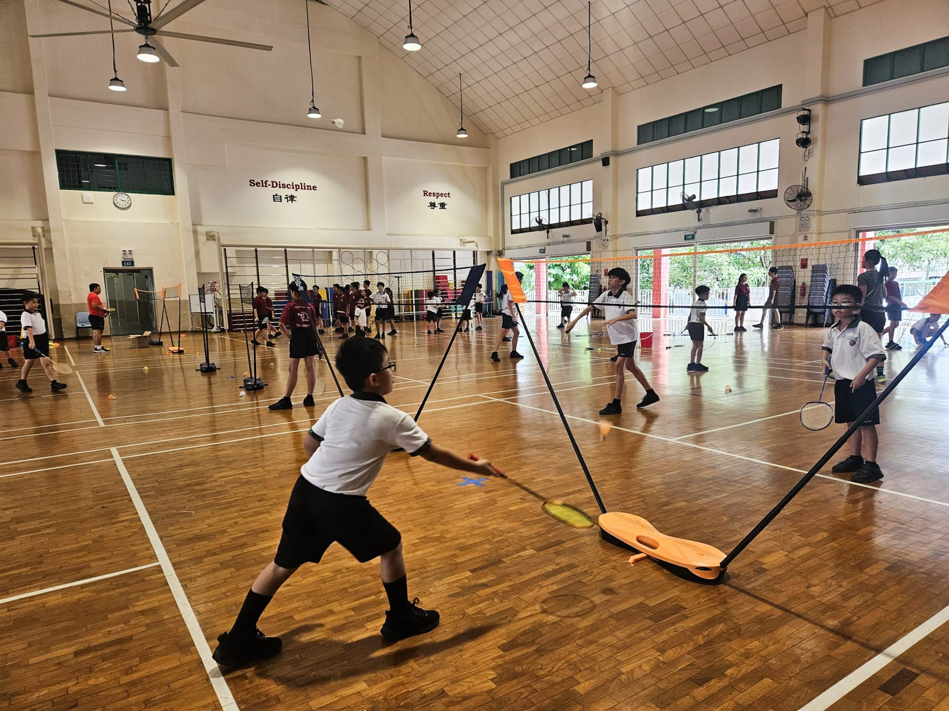 Students taking turns to rally the shuttlecock across the net while improving coordination and control
