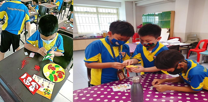 Students in blue and yellow uniforms and masks do craft activities at tables with colorful paper decorations.