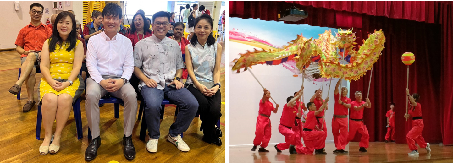 Four people seated smiling at an event, beside performers in red suits doing a dragon dance on stage.